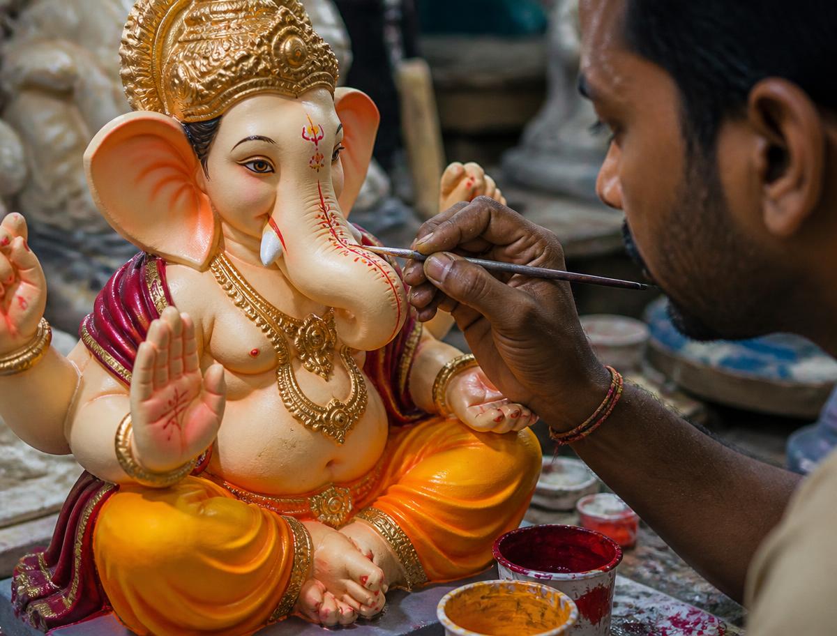 Craftsman hand-painting fine detail on a Ganpati murti with natural colours